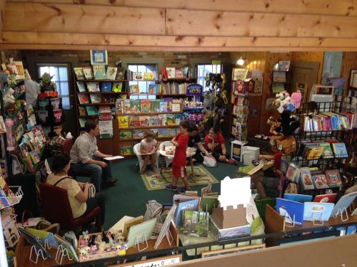 A cozy bookstore interior with shelves of books, a reading area, and children engaged in activities.