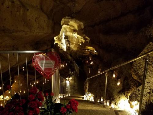 A dimly lit cave with a staircase, adorned with candles and roses, creating a romantic atmosphere.