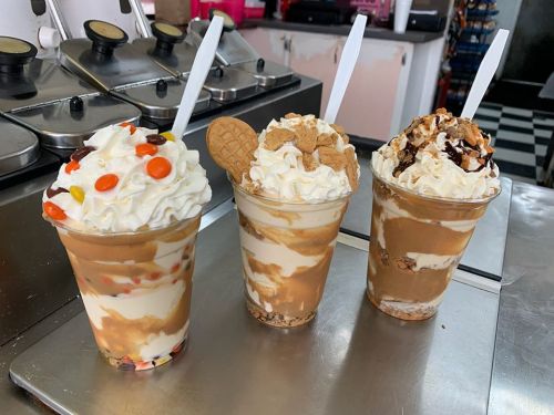 Three delicious ice cream sundaes in clear cups, topped with whipped cream, cookies, and various toppings.
