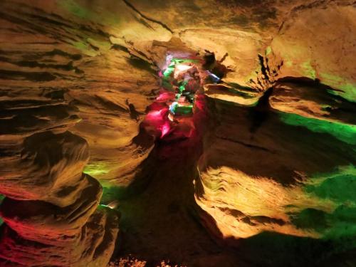 A colorful cave interior with illuminated rock formations in shades of green, red, and blue.