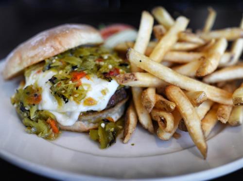 A juicy burger topped with green chilies and melted cheese, served with a side of crispy French fries.