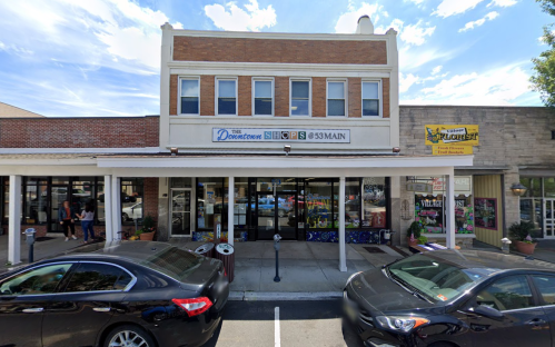 A street view of a two-story building with shops, featuring a sign that reads "The Downtown Shops 63 Main."