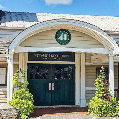 Entrance of a building with a green door, sign reading "Forty-One Bridge Street," and decorative plants on either side.