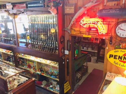A vintage shop interior filled with fishing gear, collectibles, and neon signs, creating a nostalgic atmosphere.