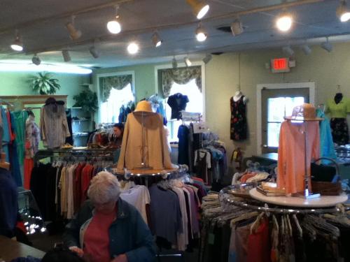 A clothing store interior with racks of colorful garments and a customer browsing through the selection.