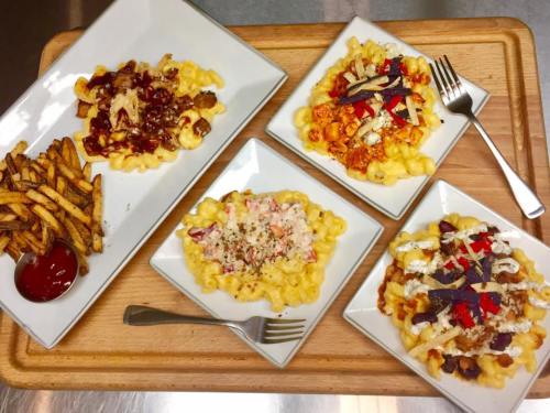 Four plates of macaroni and cheese dishes with various toppings, accompanied by a side of fries and ketchup.