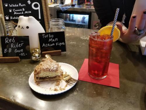 A dessert slice on a plate next to a colorful drink with a straw, set on a bar counter with playful decor.