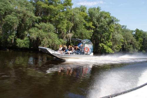 A group of people enjoying an airboat ride on a river surrounded by lush greenery.