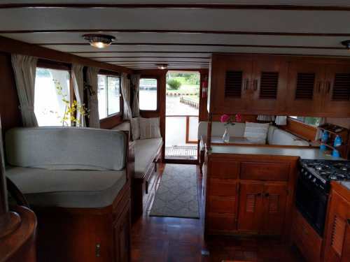 Interior of a boat featuring wooden cabinetry, seating areas, and large windows with natural light.
