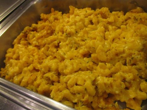 A close-up of creamy macaroni and cheese, baked until golden and bubbly in a metal serving tray.