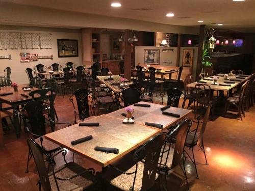 A cozy restaurant interior with wooden tables, black chairs, and soft lighting, set for dining with flowers on tables.