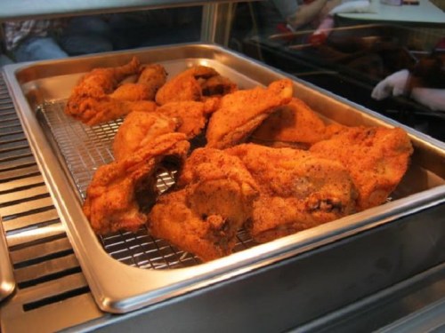 A tray of crispy, golden-brown fried chicken pieces resting on a wire rack.