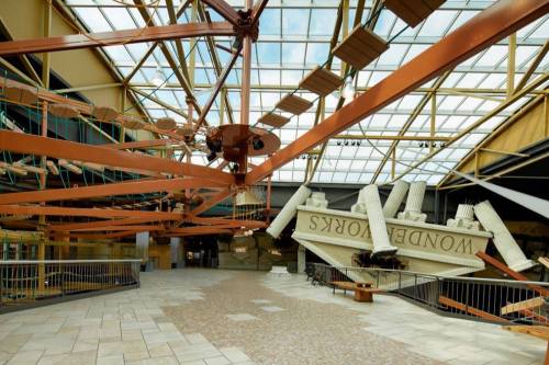 Interior of a museum with a tilted structure, showcasing a dramatic architectural design and scattered columns.