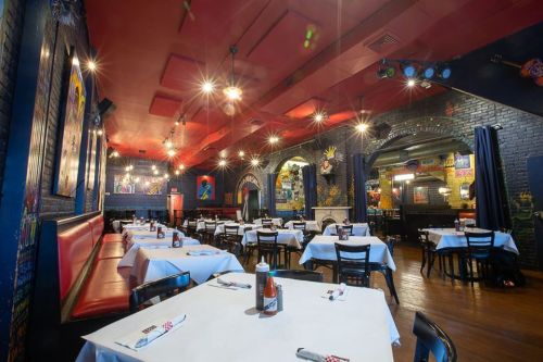 A vibrant restaurant interior with red booths, white tablecloths, and colorful artwork on the walls.