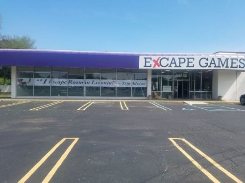 Exterior of Excape Games building with a large sign and parking lot, featuring a Trip Advisor quote about an escape room.