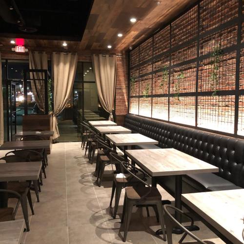 Interior of a modern restaurant featuring wooden walls, leather seating, and tables arranged along a bright, spacious layout.