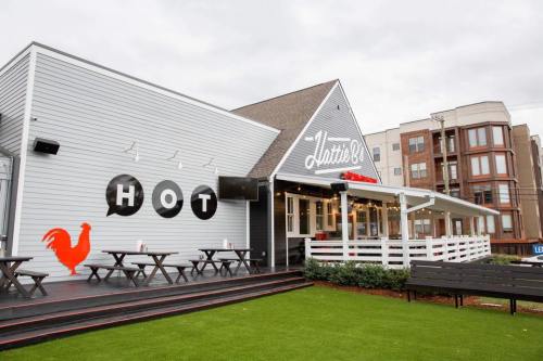 Exterior of a restaurant with a sign reading "Lutie's" and a red rooster logo, featuring outdoor seating on green grass.