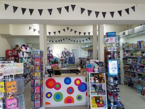 Brightly lit store interior with colorful displays of toys, games, and crafts, featuring a welcoming checkout area.