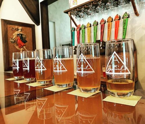 A row of glasses filled with different craft beers on a bar, with colorful tap handles in the background.