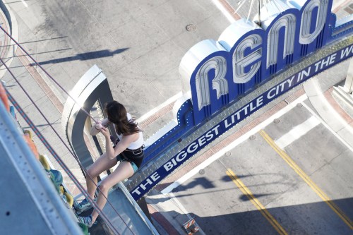 A person rappelling down a building near the "Reno" sign, showcasing the city's vibrant atmosphere.