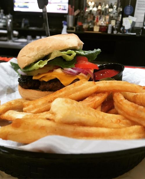 A juicy burger with lettuce, tomato, onion, and cheese, served with crispy fries and a side of ketchup.