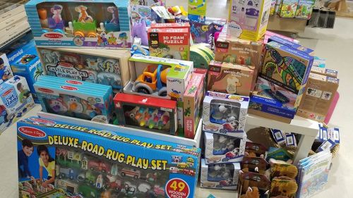 A colorful assortment of toys and games stacked together, including puzzles, playsets, and educational items.