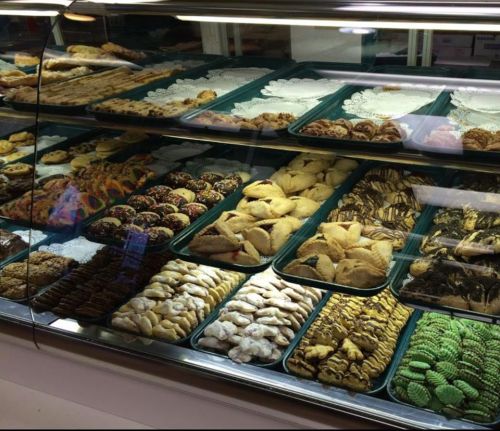 A display case filled with a variety of colorful cookies and pastries, arranged neatly on trays.
