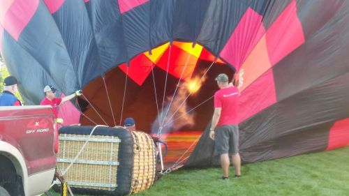 A hot air balloon being inflated, with crew members managing the process and a truck nearby.