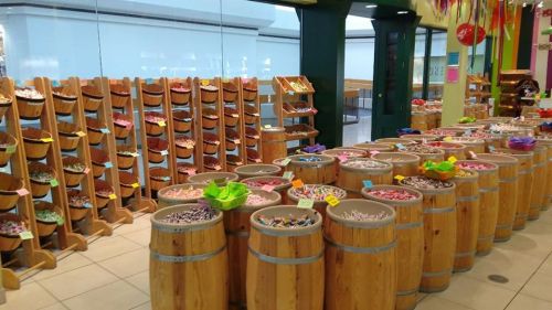 Colorful candy display with wooden barrels and shelves filled with various sweets in a bright store.