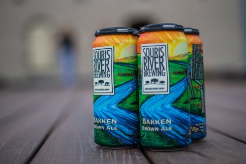 Four cans of Bakken Brown Ale from Squiris River Brewing, featuring a colorful landscape design.