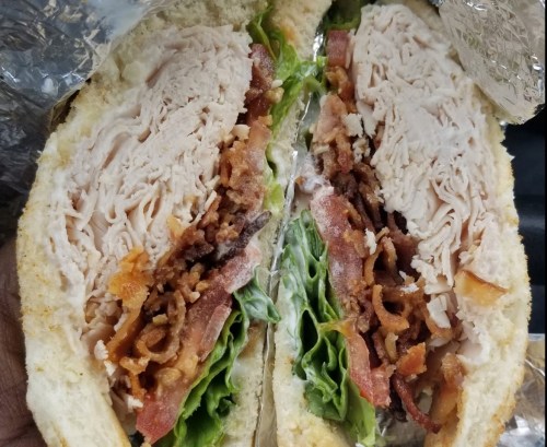 A close-up of a sandwich filled with turkey, bacon, lettuce, and mayonnaise, cut in half to show the layers.