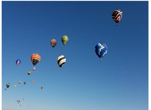 A vibrant array of colorful hot air balloons floating against a clear blue sky.