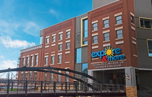 Exterior of the Explore & More Children's Museum, featuring a brick facade and a bridge in front.