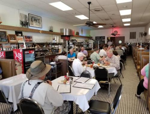 A busy diner with patrons seated at tables, enjoying meals in a cozy, retro-style setting.