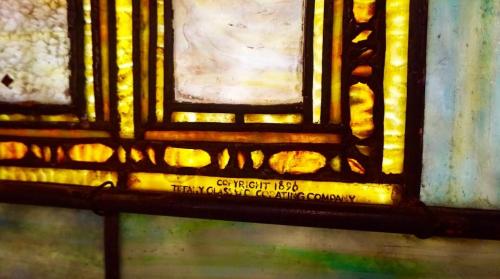 Close-up of a stained glass panel featuring vibrant colors and the inscription "Copyright 1890 Tiffany Glass Co."