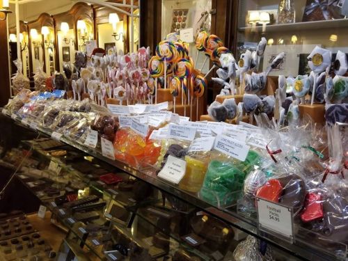 A colorful display of various candies and chocolates in a glass case, with price tags visible.