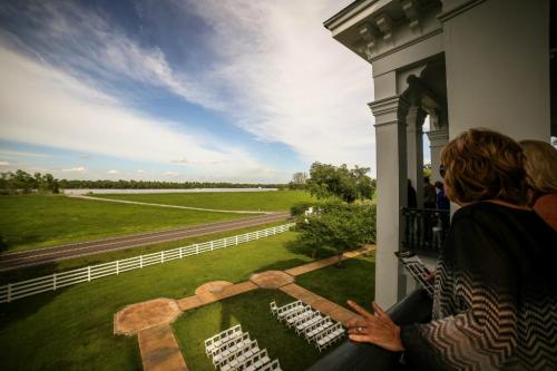 View from a balcony overlooking a green landscape with a road and rows of white chairs set up for an event.