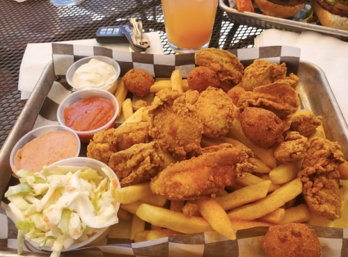 A tray of golden fried chicken, French fries, and dipping sauces, with a side of coleslaw.