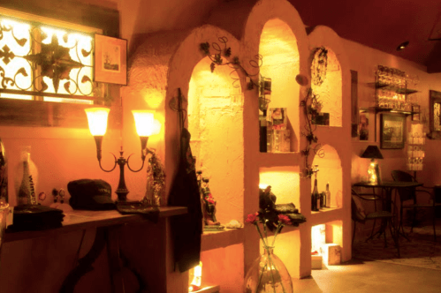 Cozy interior with warm lighting, decorative shelves, and a small seating area, creating an inviting atmosphere.