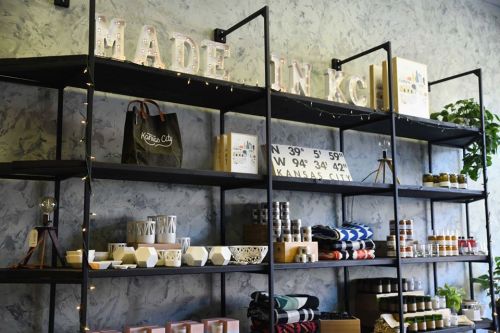 Shelves displaying various products with "MADE IN KC" sign, featuring jars, bags, and decorative items.