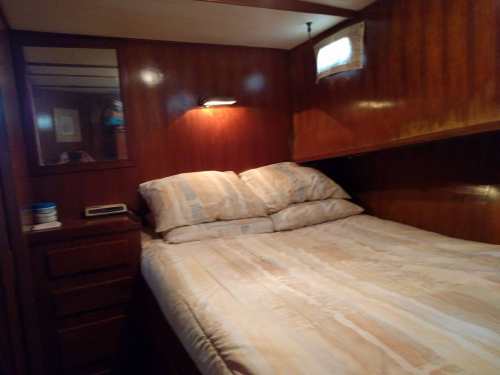 Cozy cabin interior with a double bed, wooden paneling, and a small window, creating a warm atmosphere.