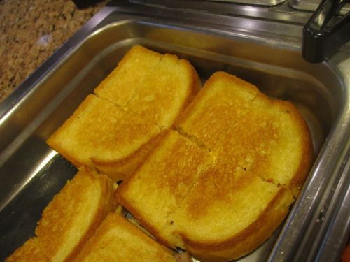 Golden-brown grilled cheese sandwiches cut into squares, arranged in a metal tray.