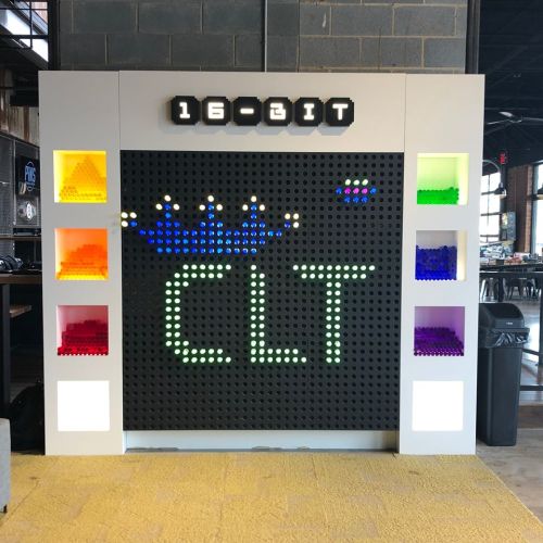 Colorful display featuring "16-BIT CLT" in lights, surrounded by vibrant LEGO bricks in a modern setting.