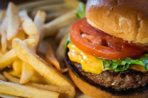 A juicy burger with lettuce, tomato, and cheese, served with a side of golden French fries.