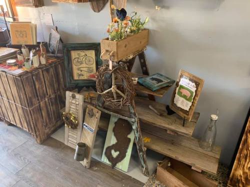 A rustic display featuring wooden decor, plants, and framed art in a cozy shop setting.
