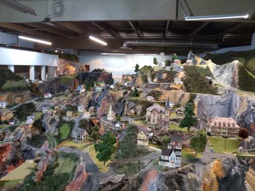 A detailed miniature landscape featuring hills, houses, and trees, showcasing intricate model scenery.