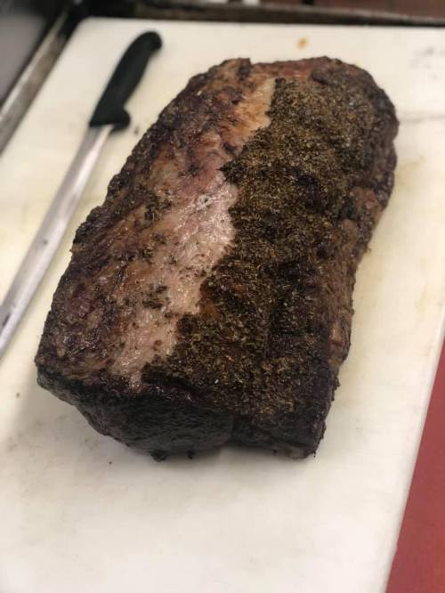 A large, seasoned roast beef resting on a cutting board, with a knife nearby.