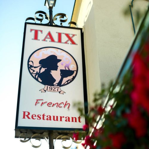 Sign for Taix French Restaurant, established in 1927, featuring a silhouette of a woman and decorative elements.