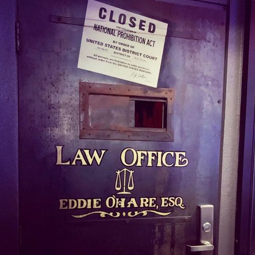 A closed law office door with a sign about the National Prohibition Act and the name Eddie O'Hare, Esq.