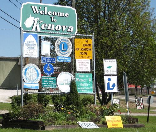 Welcome sign for Kenova, featuring various community and organizational signs, surrounded by greenery.